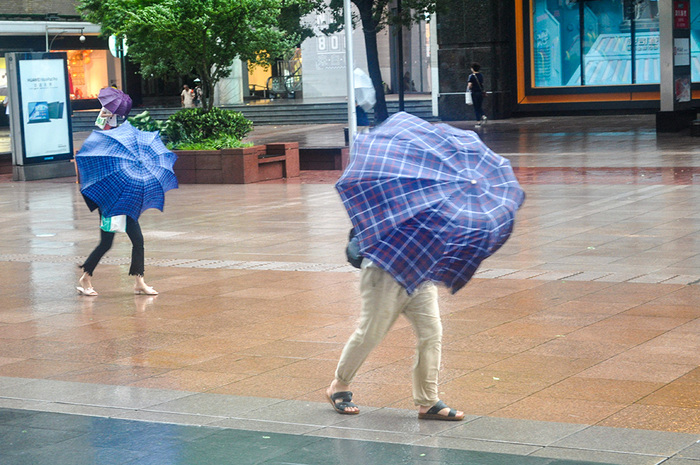 受台风"烟花"影响,上海风雨交加,南京路步行街市民游客冒风雨出行